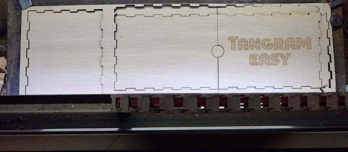 Plywood sheet with wooden box parts being laser-cut for Tangram Easy