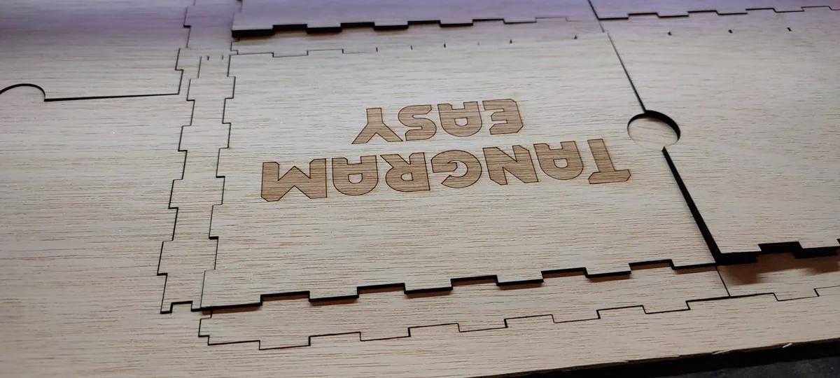 Close-up of the engraved Tangram Easy logo on a plywood box panel